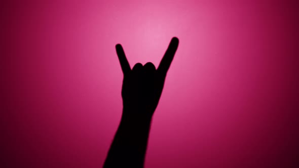 Man Showing Rock and Roll Gesture with Fingers Isolated on Pink Background