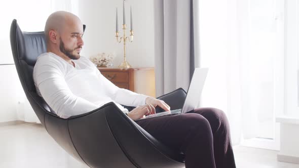 Bearded businessman working at home sitting in armchair. Business and investments concepts.