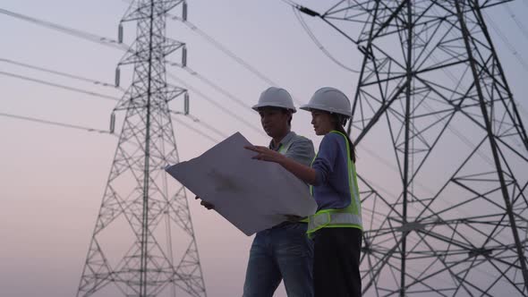 Two specialist electrical engineer working near to High voltage tower.