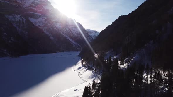 Aerial view over a wonderful valley with a frozen lake and two big snowy mountains in Klöntal Switze