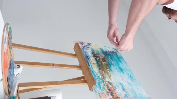 A Modern Artist Working in the Studio Emotionally Paints on a Large White Canvas with a Brush