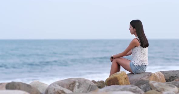 Woman sitting at beach and looking far away