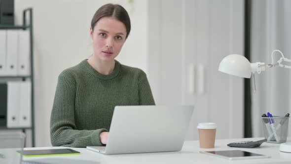 Young Woman with Laptop Shaking Head in Approval 