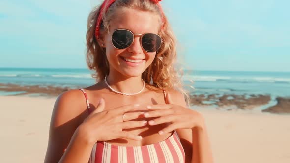 Young Cheerful Blonde Caucasian Woman in Sunglasses Walking Along Sea Beach