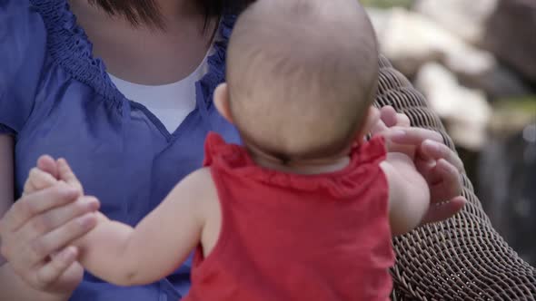 Mother with baby outside sitting in a chair.