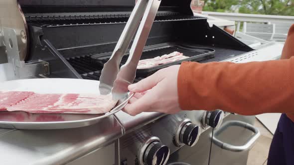 Cooking bacon stips on an outdoor gas grill.