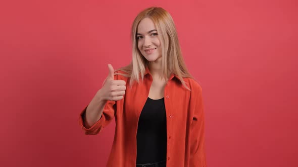 Portrait of Attractive Young Woman Showing a Thumbs Up on Red Background