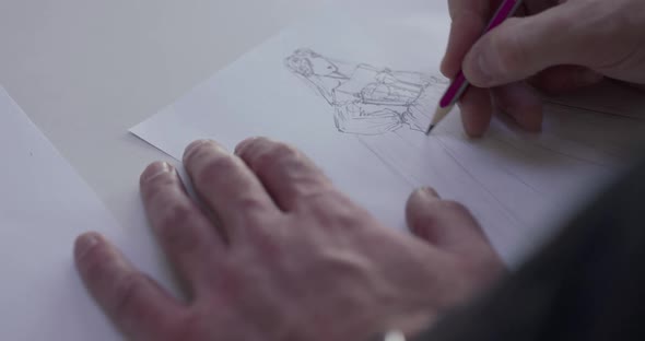 Top View of Male Designer's Hand Draws a Wedding Dress Sketch on Paper