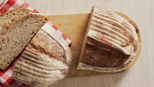 Video of loaf of bread on chopping board on a wooden surface