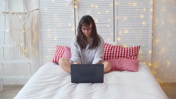 Woman Using Laptop on the Bed