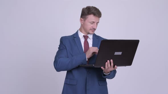 Happy Bearded Businessman Thinking While Using Laptop