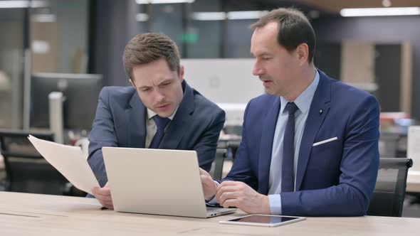 Business People Working on Laptop with Documents in Office