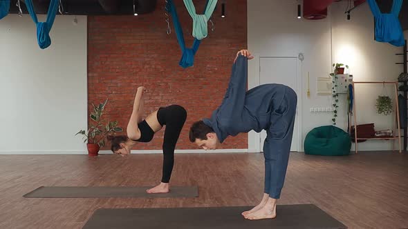 Man and Woman Doing Synchronously Tilt Exercise on Floor Mat in Yoga Studio