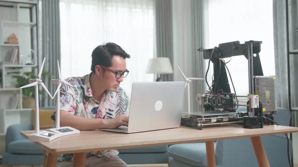 Asian Man Working With Model Wind Turbines And 3D Printer At Home