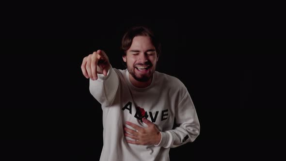 Trendy Young Man laughing at camera, pointing gesture, wide, black background