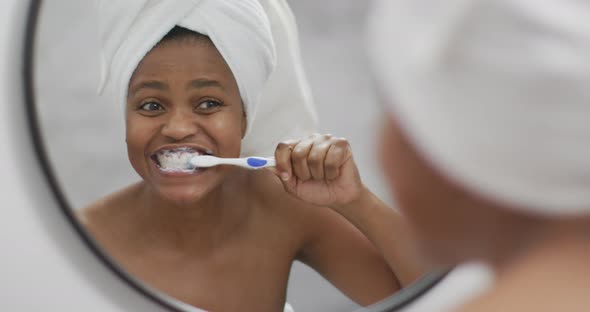 Happy african american woman brushing teeth in bathroom