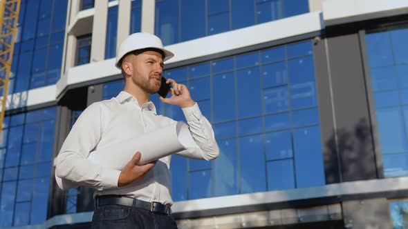 The Engineerarchitect Holds a Roll with a Drawing of the Project and Talks on a Cell Phone