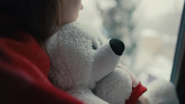 Woman with Teddy Bear Looking Outside the Window