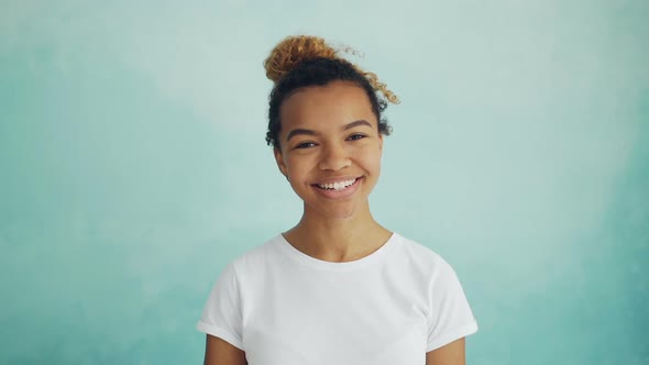 Portrait of Cheerful Young Woman with Curly Hair Looking at Camera and Smiling