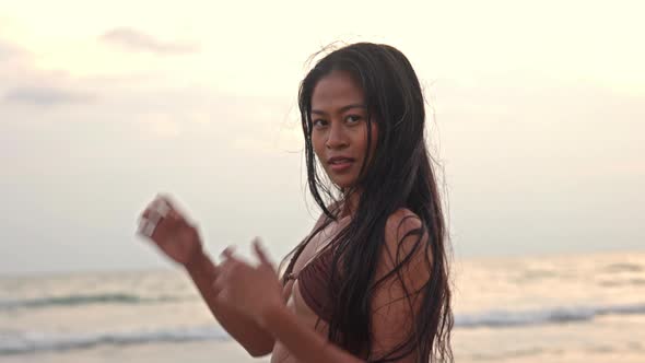 Beautiful Young Woman Looking At Camera On Beach At Sunset