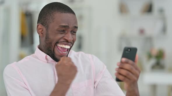 Portrait of African Man Celebrating Success on Smartphone