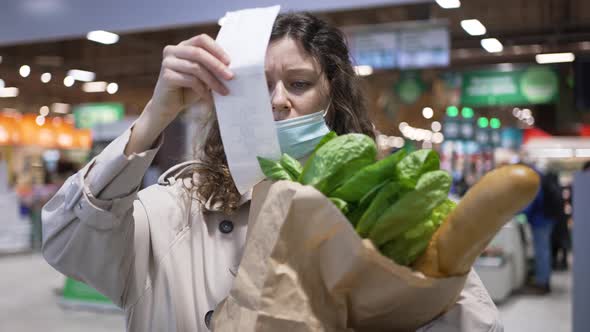 Woman Buyer Takes Out a Paper Check From a Grocery Bag in a Supermarket and is Very Surprised at the