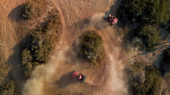 Aerial closeup of two four wheelers racing in circles on a dirt path in cavo Greko
