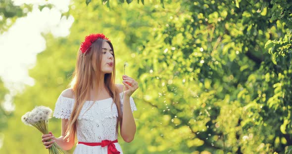 Happy Girl Walks with Flowers Across the Meadow on a Sunny Day