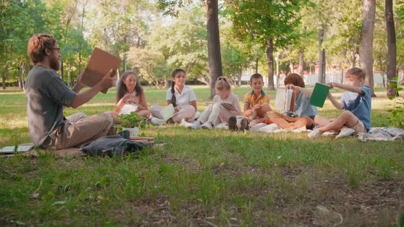 Schoolchildren and Male Teacher Having Lesson in Park