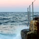 Sea Waves with Splashes Break on the Rocky Shore on Which the Bridge is Located - VideoHive Item for Sale
