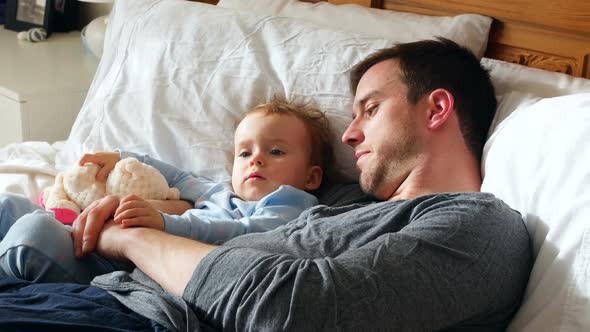 Father and baby boy relaxing in bedroom