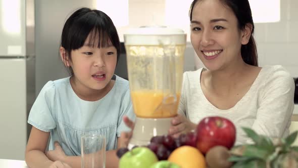 Mother and daughter cooking orange smoothie