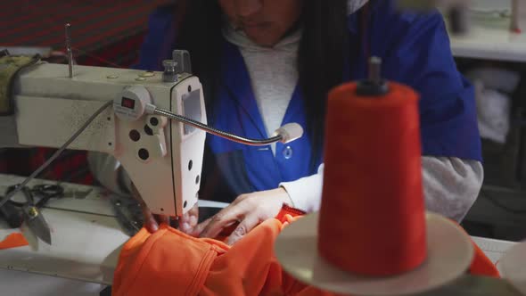 Mixed race woman using sewing machine in factory