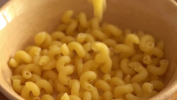 Spiral Shaped Pasta Falling Into a Brown Plate in Slow Motion