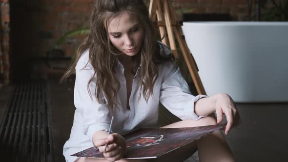 Girl Artist Paints a Picture in the Home Studio. Portrait of the Painter in the Loft