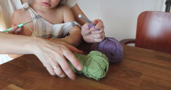 Mother and daughter crocheting at home