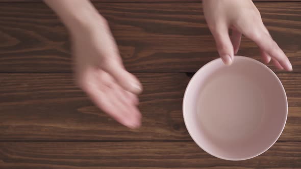 Female hands put bowls on wooden textured table. Three bowls next to each other on kitchen table