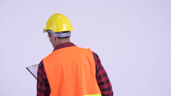 Rear View of Young Hispanic Man Construction Worker Reading on Clipboard