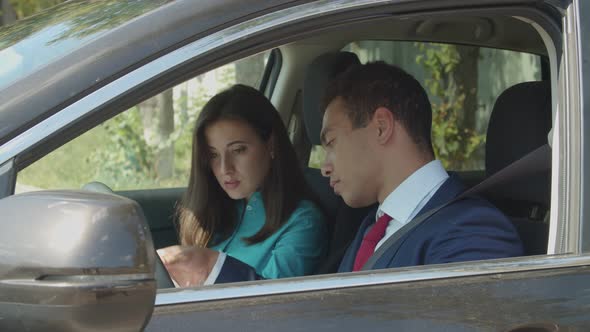 Mixed Race Businesspeople in Car Analyze Documents