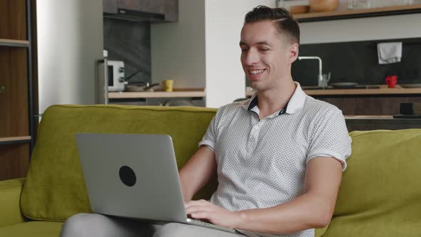 Young Man Freelancer Using Laptop Device on Sofa at Home Office, Portrait of Male Working Distantly