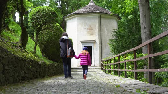 A mother and her little daughter carrying a teddy bear visiting the sacred mountain of Varallo chris