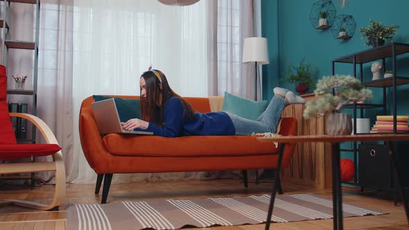 Cheerful Young Woman Lying on Sofa Using Laptop Pc Share Messages on Social Media Application