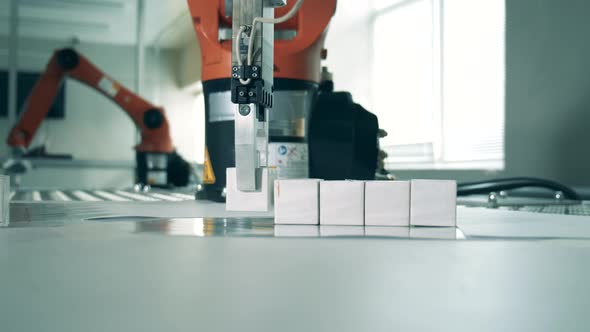 Small Cubes Are Being Put in a Row By a Robotic Arm. Industrial Robotic Manipulator