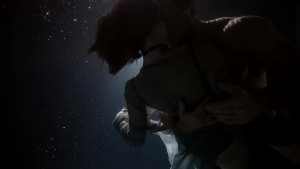 Man and Woman are Embracing Underwater in Darkness