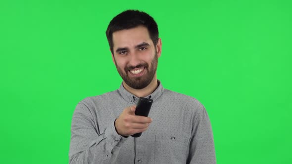 Portrait of Brunette Guy with TV Remote in His Hand, Switching on TV. Green Screen