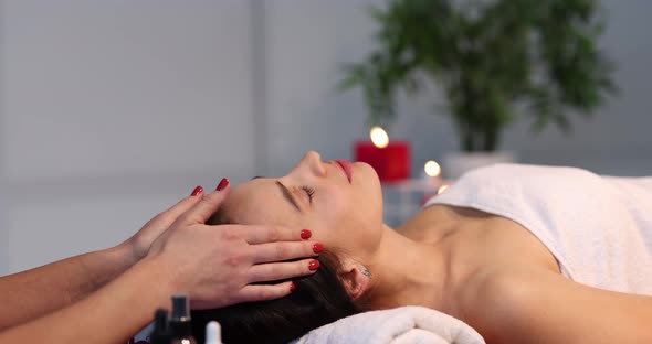 Happy Beautiful Adult Woman with Closed Eyes Receiving Head Massage with Hands