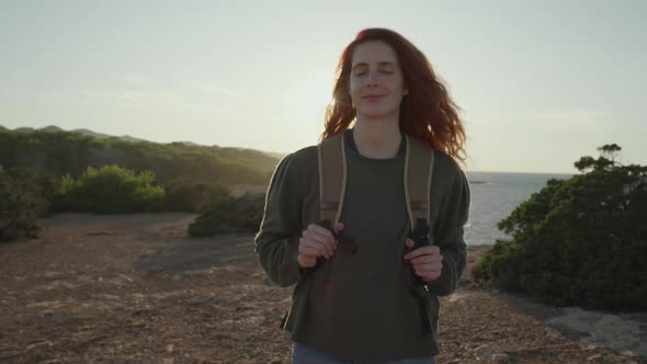 Slow motion shot of happy redheaded woman walking at coast, Ibiza