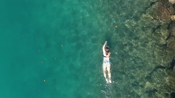 A female snorkeler in a bathing costume swimming along in the ocean
