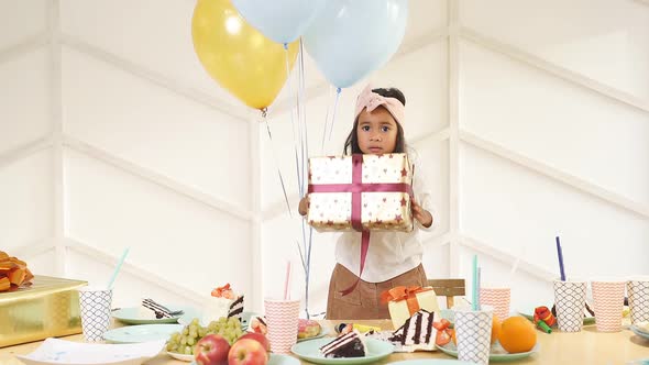 Cite Child Girl in Birthday Cap Gets Gifts By Guests