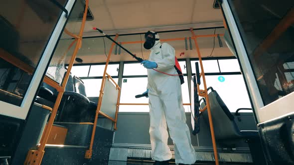 A Person in a Protection Suit Is Doing Chemical Treatment in a Bus